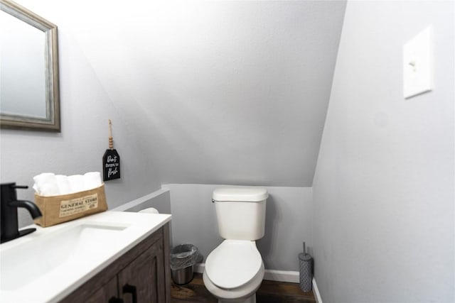 bathroom with vanity, toilet, lofted ceiling, and wood-type flooring