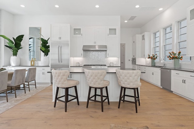 kitchen with white cabinetry, a wealth of natural light, light hardwood / wood-style flooring, and stainless steel dishwasher