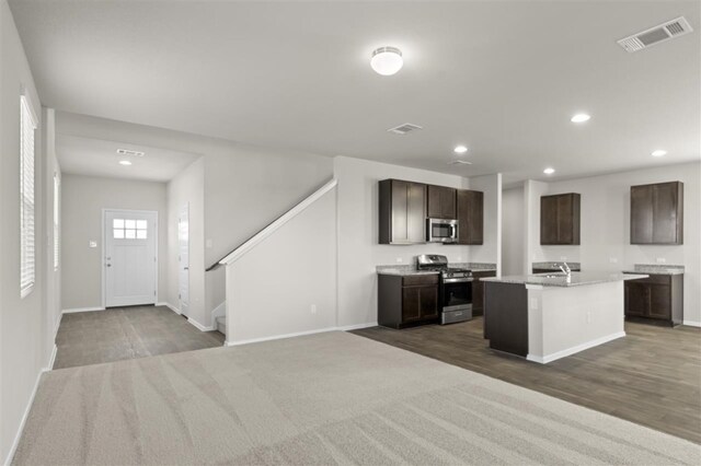 kitchen featuring dark brown cabinetry, a kitchen island with sink, dark hardwood / wood-style flooring, and appliances with stainless steel finishes