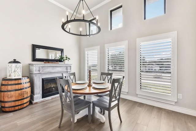 dining space featuring wood-type flooring, ornamental molding, a wealth of natural light, and a towering ceiling