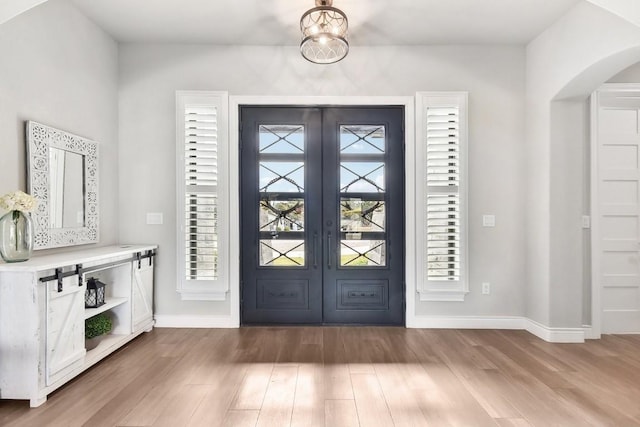 foyer with hardwood / wood-style floors, an inviting chandelier, and french doors