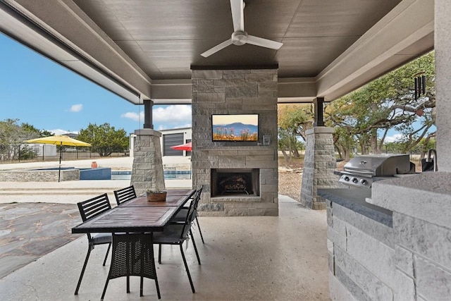 view of patio / terrace with an outdoor stone fireplace, ceiling fan, exterior kitchen, and area for grilling