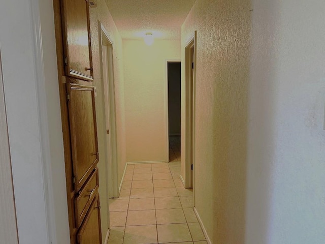 hallway featuring light tile patterned floors and a textured ceiling