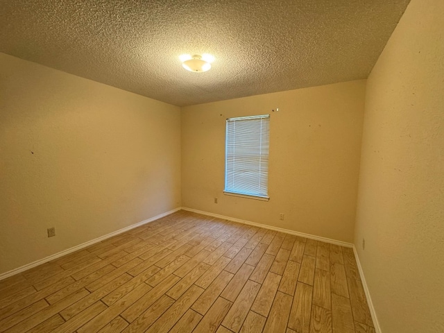 empty room featuring a textured ceiling and light hardwood / wood-style flooring