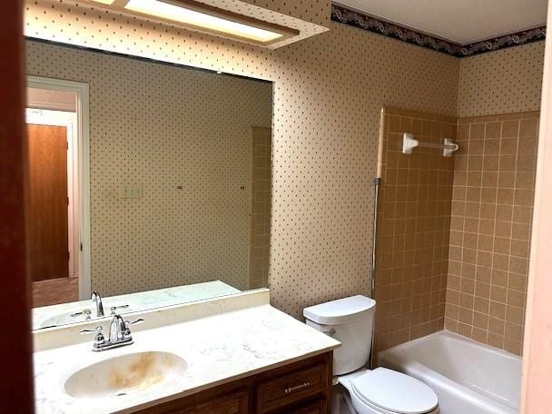 full bathroom with vanity, tiled shower / bath combo, and toilet