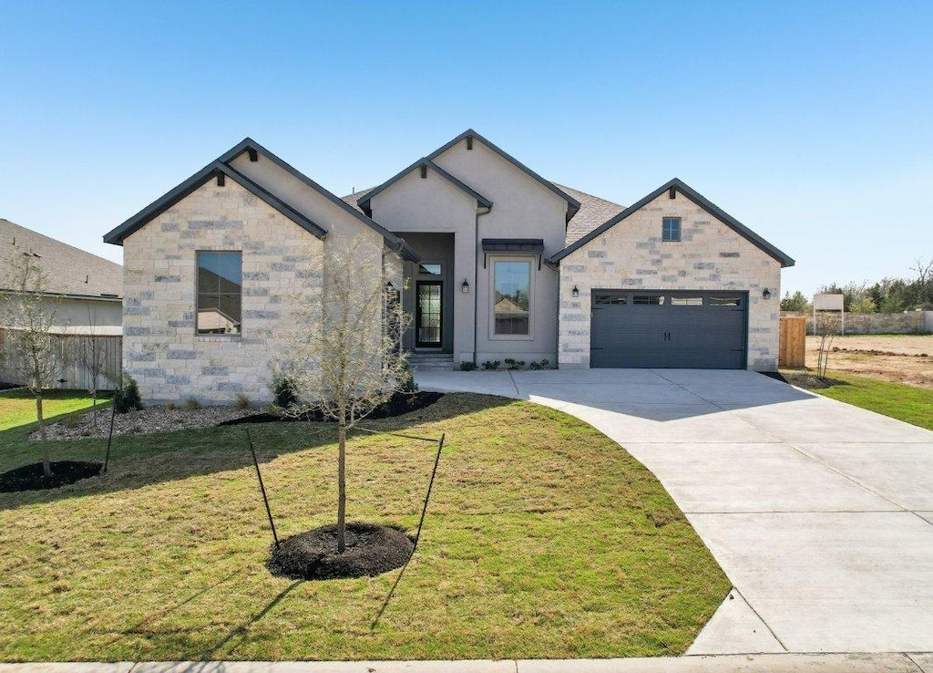 166 Kellogg Ln, Bastrop, TX 78602 - french country style house with concrete driveway, stone siding, and an attached garage