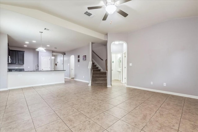 unfurnished living room with ceiling fan, sink, light tile patterned floors, and lofted ceiling