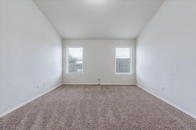 carpeted empty room featuring plenty of natural light, baseboards, and lofted ceiling