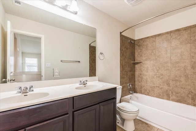 full bathroom featuring tile patterned flooring, vanity, tiled shower / bath combo, and toilet