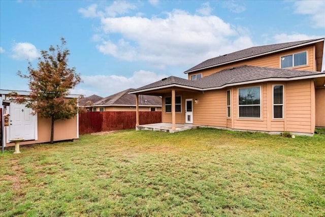back of house featuring an outbuilding, a shed, a yard, a patio area, and fence