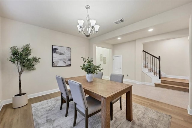 dining space with hardwood / wood-style floors and an inviting chandelier