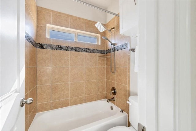 bathroom with toilet and tiled shower / bath