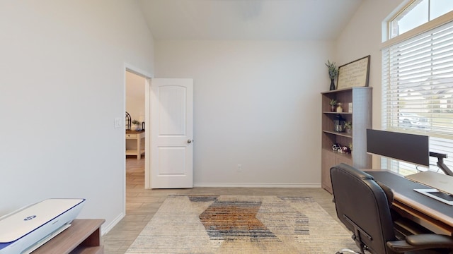 home office featuring light hardwood / wood-style floors and vaulted ceiling