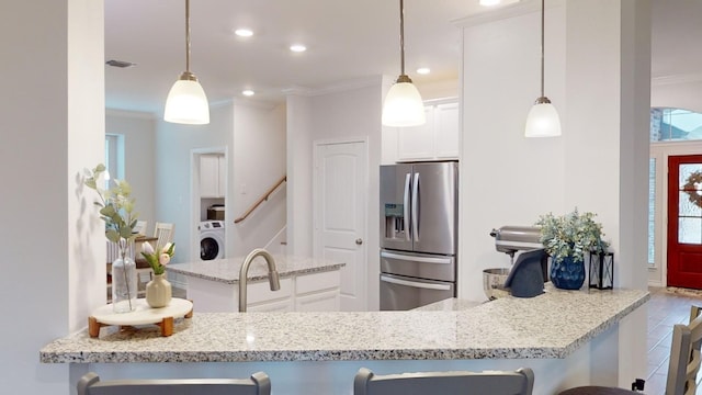 kitchen featuring stainless steel refrigerator with ice dispenser, crown molding, white cabinets, washer / dryer, and hanging light fixtures