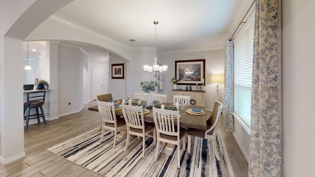 dining room with an inviting chandelier, crown molding, a wealth of natural light, and light hardwood / wood-style flooring