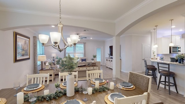 dining space with light wood-type flooring, crown molding, and a chandelier