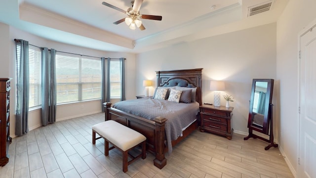 bedroom with ceiling fan, a raised ceiling, crown molding, and light hardwood / wood-style flooring