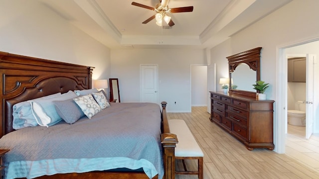 bedroom with a raised ceiling, ceiling fan, ornamental molding, connected bathroom, and light hardwood / wood-style floors