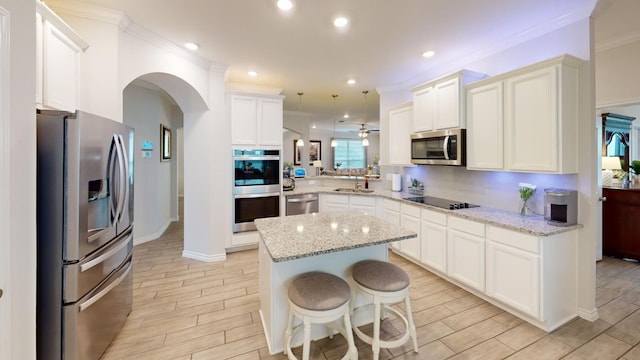 kitchen featuring light wood-type flooring, stainless steel appliances, pendant lighting, a kitchen island, and a breakfast bar area