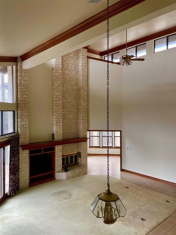 4324 Far W Blvd, Austin, TX 78731 - unfurnished living room featuring crown molding, a fireplace, ceiling fan, tile patterned flooring, and a towering ceiling