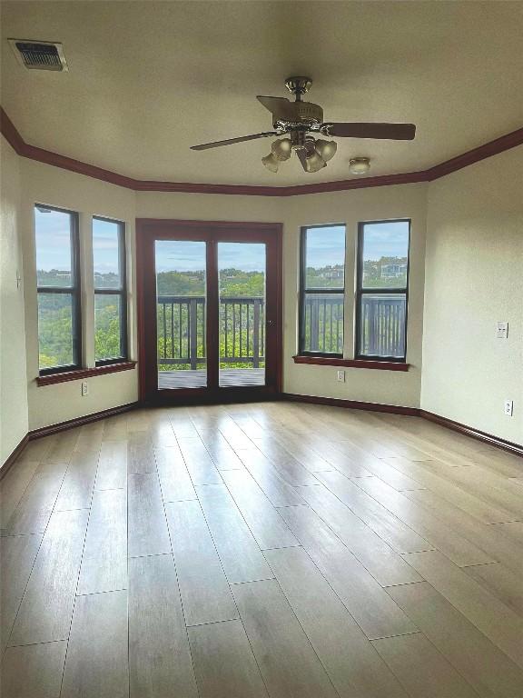 empty room with ornamental molding, light hardwood / wood-style floors, and ceiling fan