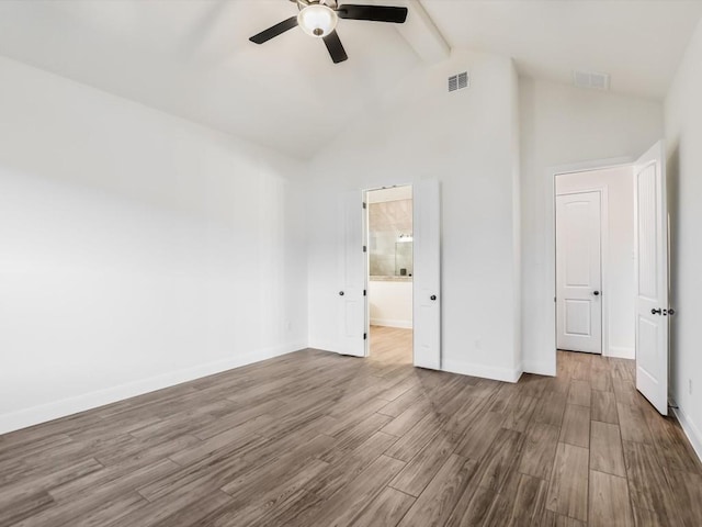 unfurnished bedroom featuring beamed ceiling, ceiling fan, wood-type flooring, and connected bathroom