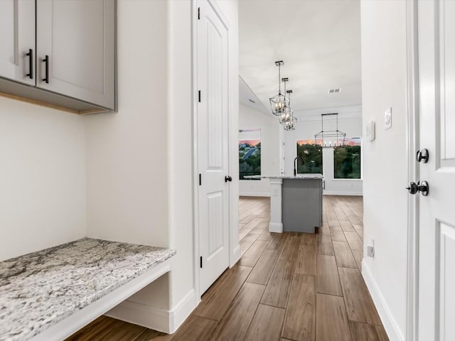 mudroom featuring dark wood-type flooring and a notable chandelier