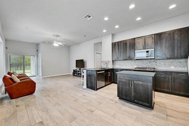 kitchen featuring appliances with stainless steel finishes, a center island, ceiling fan, and dark brown cabinets