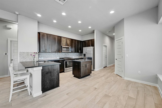 kitchen with sink, a kitchen island, stainless steel appliances, a kitchen bar, and kitchen peninsula