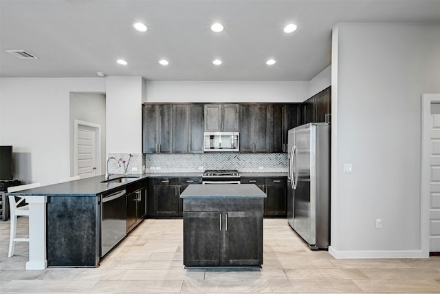 kitchen with stainless steel appliances, tasteful backsplash, a kitchen island, and sink