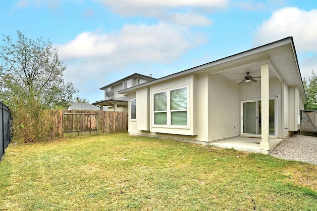 rear view of property with ceiling fan, a patio, and a lawn