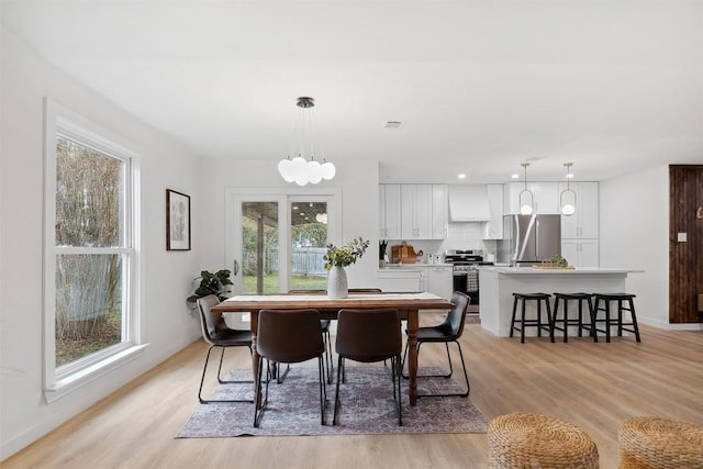 dining space featuring light wood-type flooring and an inviting chandelier