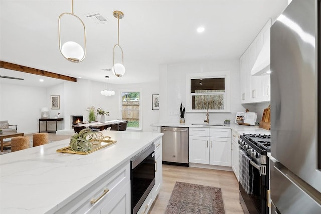 kitchen featuring pendant lighting, white cabinets, sink, appliances with stainless steel finishes, and light hardwood / wood-style floors