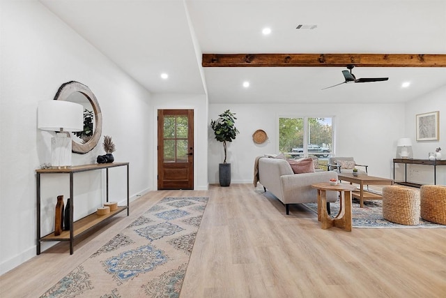 living room featuring beamed ceiling, light hardwood / wood-style flooring, a wealth of natural light, and ceiling fan