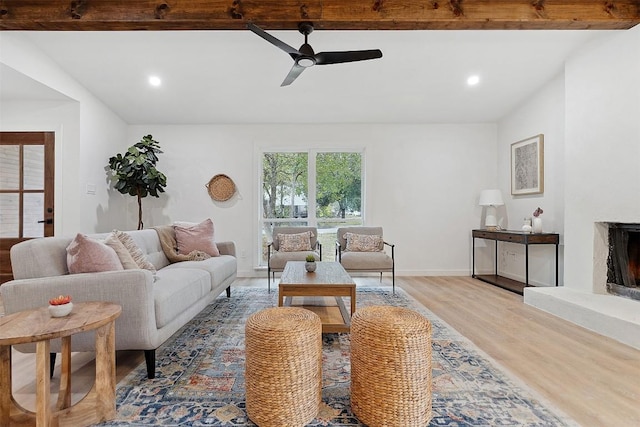 living room featuring beam ceiling, light wood-type flooring, and ceiling fan