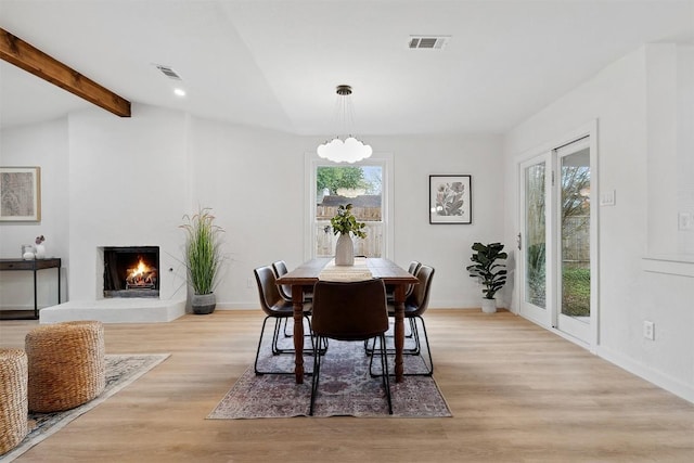 dining area featuring vaulted ceiling with beams, plenty of natural light, and light hardwood / wood-style flooring