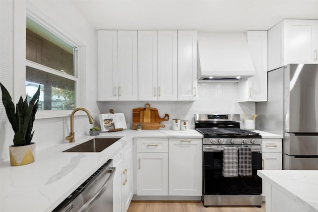 kitchen featuring white cabinets, custom exhaust hood, sink, and appliances with stainless steel finishes