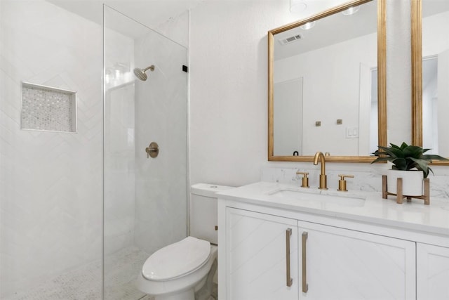 bathroom with tiled shower, vanity, and toilet