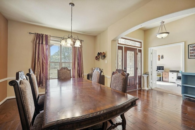 dining area featuring dark wood-type flooring and an inviting chandelier