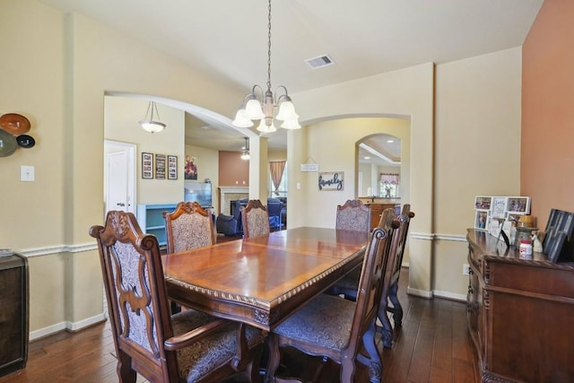 dining room with ceiling fan with notable chandelier and dark hardwood / wood-style floors