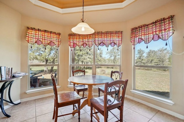 dining room with a tray ceiling, crown molding, and light tile patterned flooring