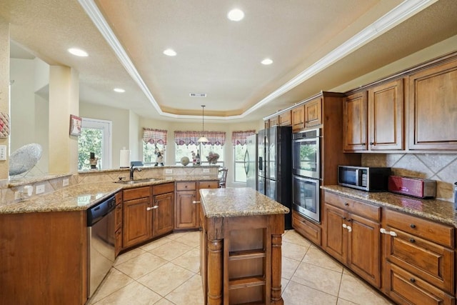 kitchen featuring sink, a center island, light stone counters, a tray ceiling, and appliances with stainless steel finishes