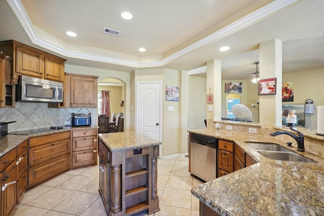 kitchen featuring sink, a center island, stainless steel appliances, light stone counters, and crown molding