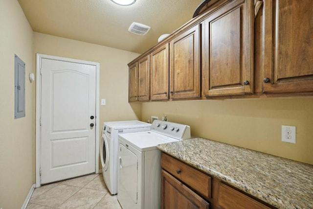 clothes washing area featuring washer and clothes dryer, cabinets, electric panel, light tile patterned floors, and a textured ceiling