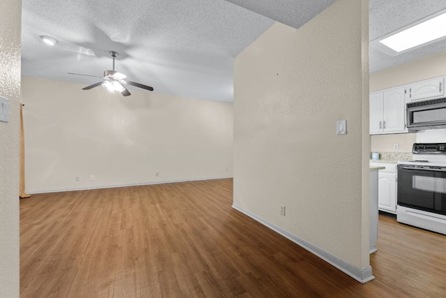 unfurnished living room featuring ceiling fan, light hardwood / wood-style floors, and a textured ceiling