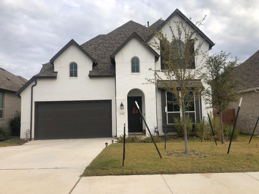 french country home featuring a garage and a front yard