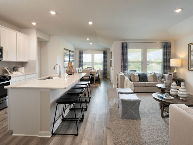 living room featuring sink, lofted ceiling, and light wood-type flooring