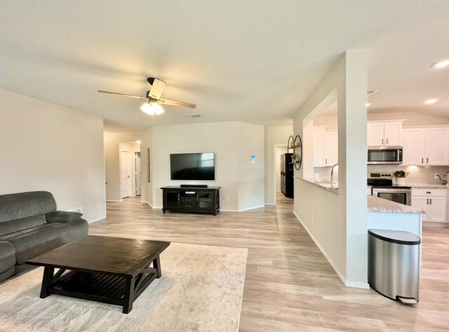 living room with ceiling fan and light hardwood / wood-style flooring