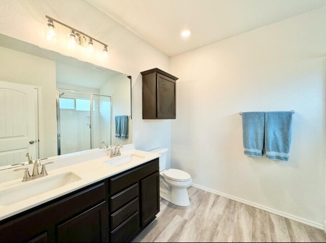 bathroom with vanity, hardwood / wood-style flooring, a shower with shower door, and toilet