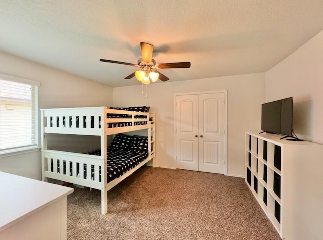 carpeted bedroom with ceiling fan, a closet, and a textured ceiling